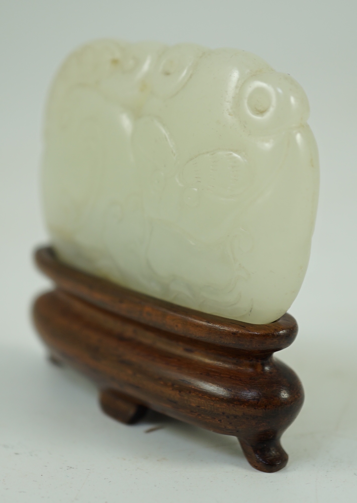 A Chinese white jade ‘tiger and dragon’ plaque, 18th/19th century 5.1 cm wide, wood stand